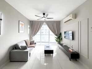 A modern living room with a sofa, a coffee table, a TV, and a ceiling fan. - Aurora Residence by Manhattan Group (Puchong)