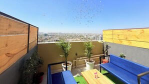 Un balcon avec un plancher en bois, un banc bleu et des plantes en pot.