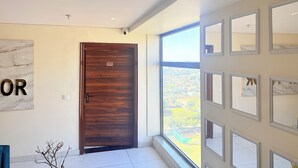 Un intérieur moderne avec une porte en bois, une grande fenêtre donnant sur la ville et un mur en marbre sur lequel on peut apercevoir un mot.