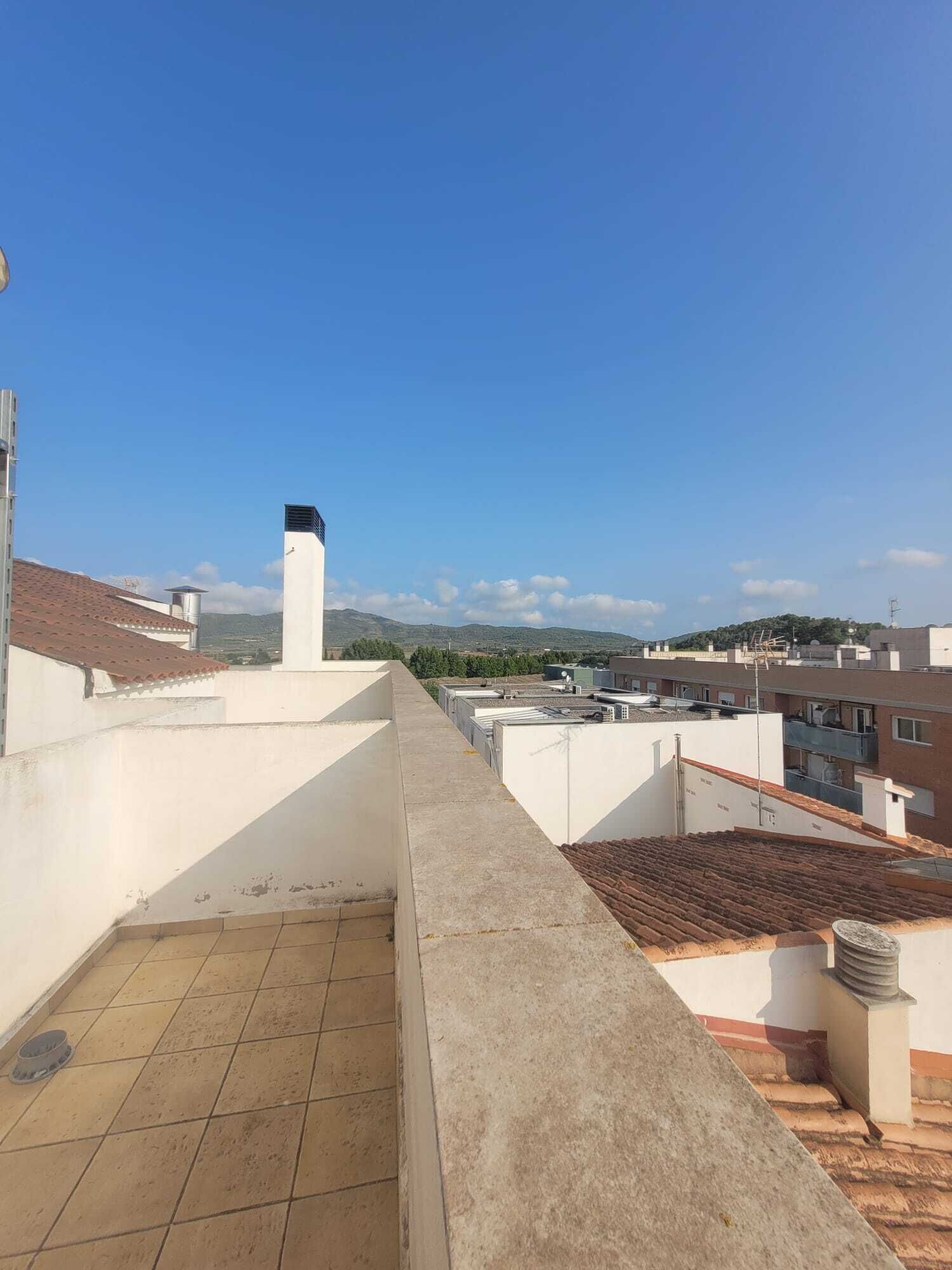 A rooftop terrace with a clear view of the surrounding buildings and distant hills.