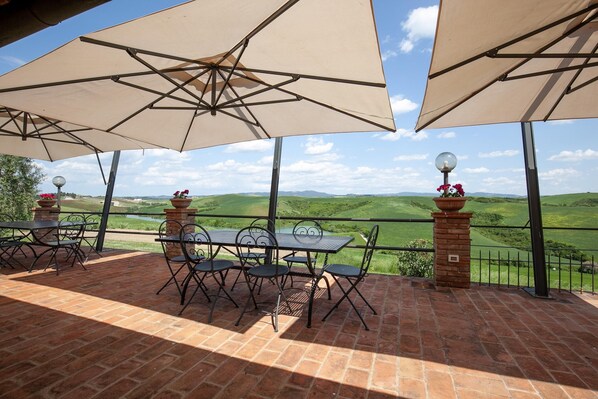 A patio with tables and chairs under large umbrellas, overlooking a scenic landscape. - Nice Apartment With Swimming Pool (Peccioli)