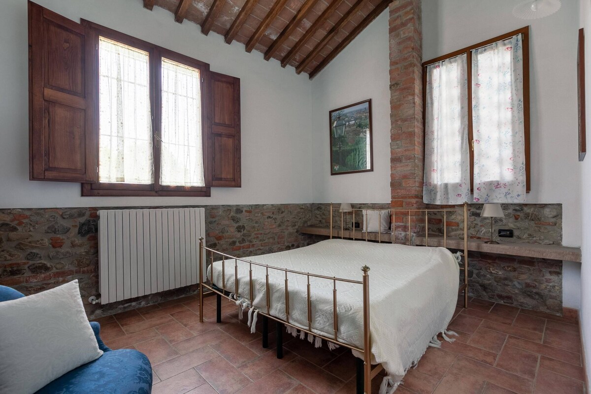 A bedroom with a bed, wooden beams, stone walls, and a radiator.