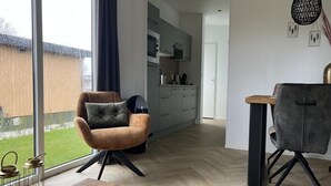 Ett modernt vardagsrum med ett stort fönster, ett matbord och två stolar.