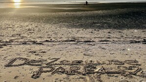 En strand med fotspår och ordet ”gott” skrivet i sanden.