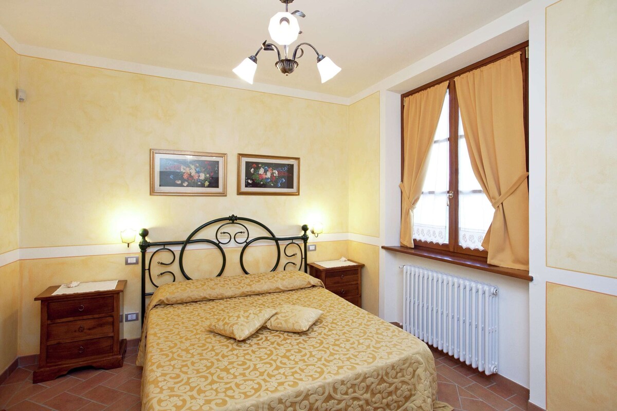Ein Schlafzimmer mit einem Bett, zwei Nachttischen, einer Heizung und einem Fenster mit Vorhängen.