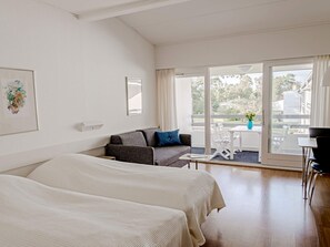 A hotel room with two beds, a sofa, a table, and a balcony with a view. - Dueodde Beach Apartments (Nexø)