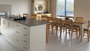A kitchen with a central island, wooden chairs, a dining table, and a window with a view.