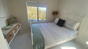 A bedroom with a bed, a window, a bedside table, and a lamp.