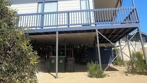 A two-story building with a balcony, a covered outdoor area, and a dirt ground.