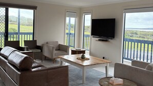 A modern living room with a sofa, chairs, a coffee table, and a TV.
