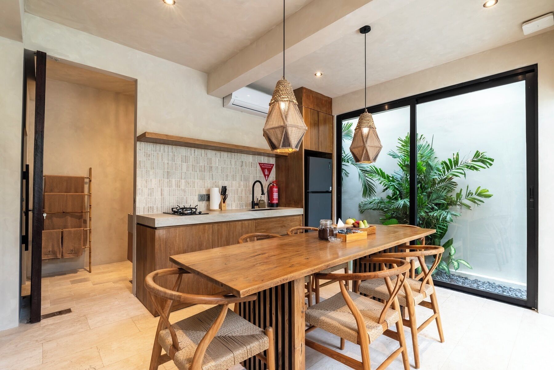 A modern kitchen with a wooden island, a dining area with a wooden table and chairs, and a large window with a view of greenery.