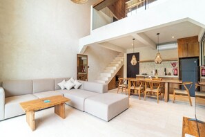 A modern living room with a sofa, a wooden coffee table, and a dining area with wooden chairs and a table. - Serene Villas Bingin, Uluwatu by Blacksand (Pecatu)