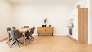 Una cocina moderna con un mueble de madera, una mesa de comedor con sillas y una planta pequeña sobre el mueble.