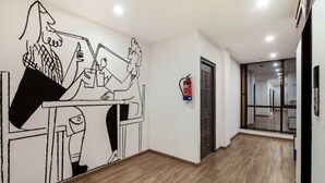 A hallway with a wooden floor, a fire extinguisher mounted on the wall, and a glass door leading to another room. - Townhouse Samaypur Badli Metro Station (New Delhi)