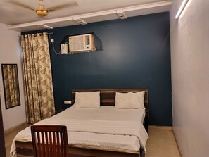 A bedroom with a bed, a chair, a ceiling fan, and an air conditioning unit. - Townhouse Samaypur Badli Metro Station (New Delhi)