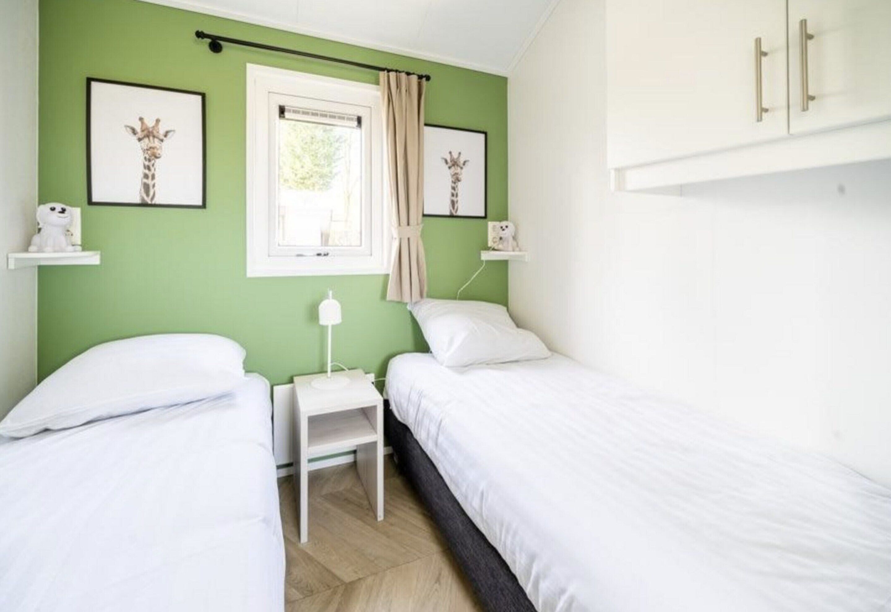 Un dormitorio con dos camas, una ventana con cortinas y obras de arte en las paredes.