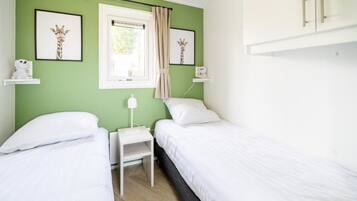 Un dormitorio con dos camas, una ventana con cortinas y obras de arte en las paredes.