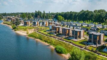 Un quartier résidentiel moderne, avec des maisons contemporaines construites le long d’une rivière, offrant des espaces ouverts et de nombreux espaces verts.