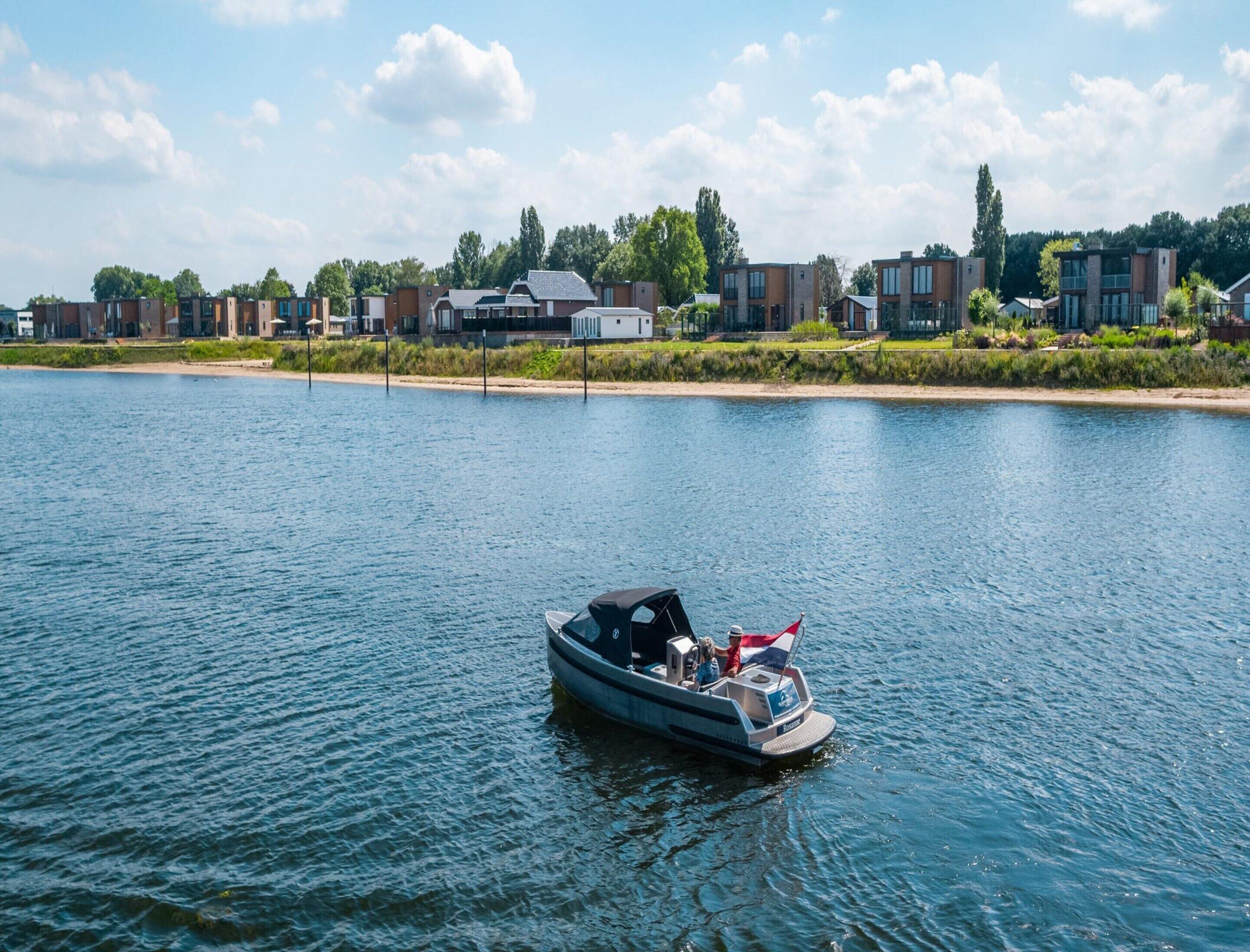 A boat on a calm river with modern buildings in the background.