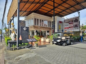 Ένα ξενοδοχείο με σκεπαστή είσοδο, ένα άγαλμα και ένα ηλεκτρικό καρότσι γκολφ.