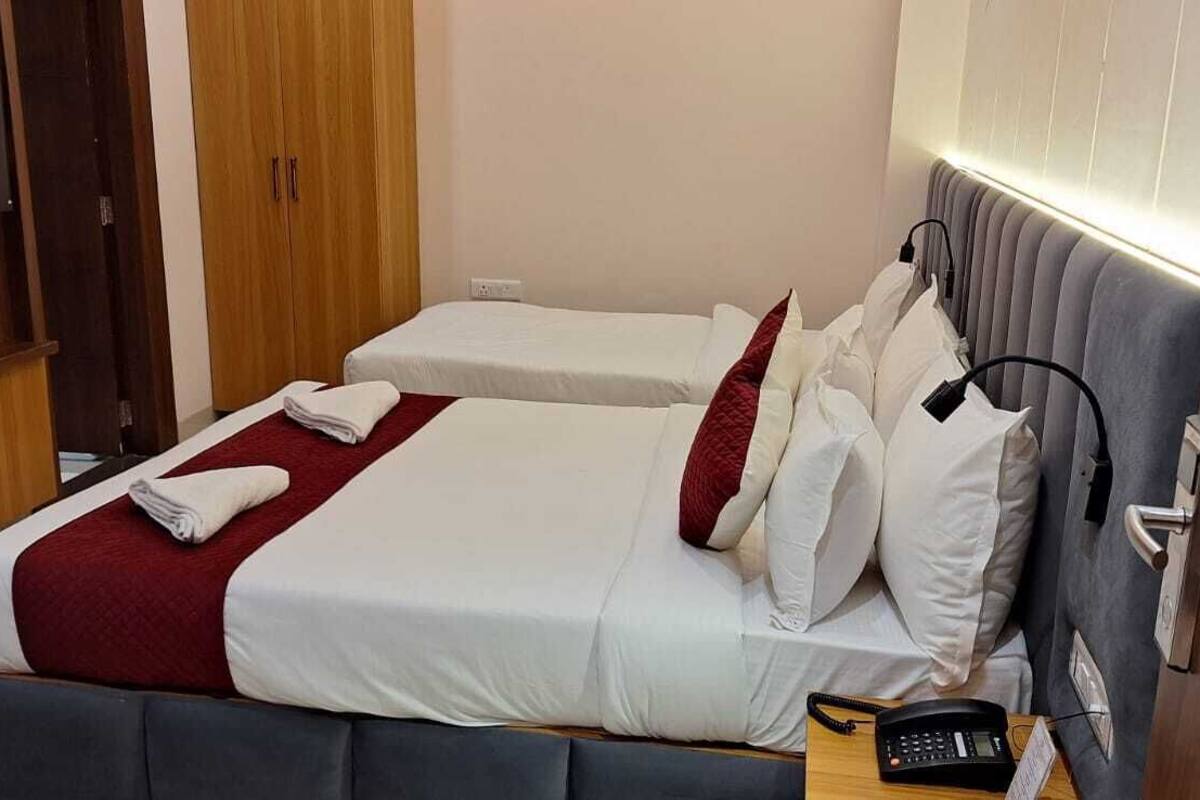 A hotel room with two beds, a TV, a bedside table with a phone, and a wardrobe.