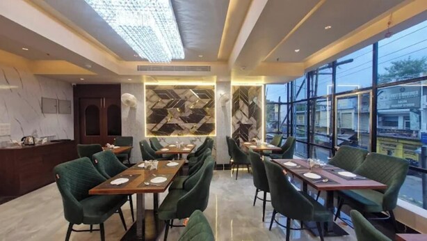 Een modern restaurant met hoge plafonds, geometrische wanddecoratie en grote ramen met uitzicht op de stad.