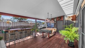 Terrassa exterior amb zona de bar, una barbacoa i una decoració de cap de vaca penjant.