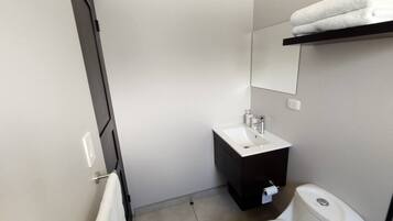 Uma casa de banho moderna com uma pia branca, armário escuro, sanita e barra de toalhas.