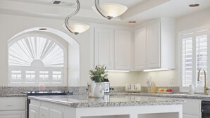 A kitchen with white cabinetry, a granite countertop, a sink, a stove, and a window with blinds. - Vegas Grand Villa - 5BR, Pool, Putting Green (Las Vegas)