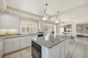 A spacious kitchen with white cabinetry, granite countertops, and a central island. - Vegas Grand Villa - 5BR, Pool, Putting Green (Las Vegas)
