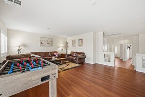A spacious living room with a foosball table, two sofas, and a coffee table. - Vegas Grand Villa - 5BR, Pool, Putting Green (Las Vegas)