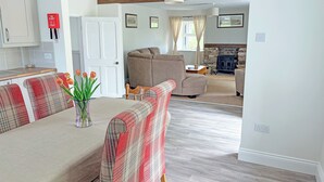A cozy living room with a sofa, a fireplace, and a dining area with a table and chairs. - 3 bedroom accommodation in Brough (Brough)