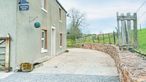 A building labeled 'High Park House' with a stone wall, a wooden gate, and a paved driveway. - 3 bedroom accommodation in Brough (Brough)