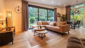 A modern living room with a sofa, coffee table, and dining area. - Drenthe Wellness Lodge for 4 (Ruinen)