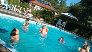 A swimming pool with people in the water, surrounded by lounge chairs and umbrellas. - Drenthe Wellness Lodge for 4 (Ruinen)
