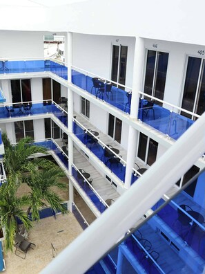 Eine mehrstufige Terrassenanlage im Freien mit blauen Geländern, mehreren Sitzbereichen und einer Palme.