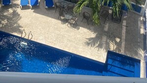 A multi-story hotel with a blue roof, a pool, and outdoor seating. - Chambre Double #300 de l'Hôtel Legendario (Sosúa)