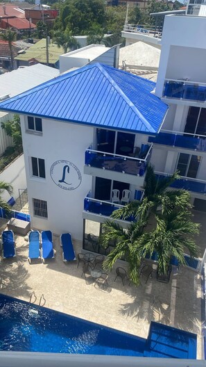 Ein mehrstöckiges Hotel mit blauem Dach, Schwimmbecken und Außenbereich.