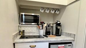 Una cucina compatta con microonde, macchina per il caffè e frigorifero.