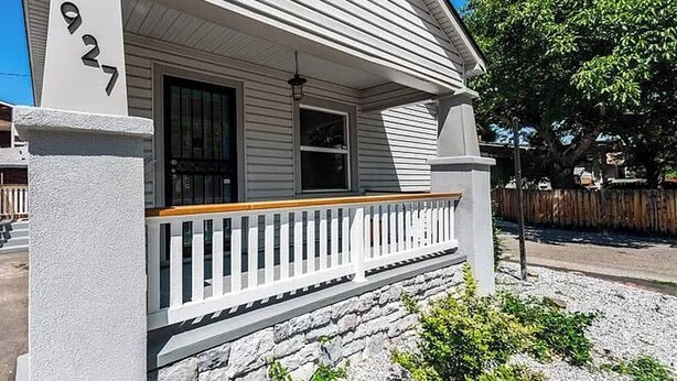 Una casa con un portico, fondamenta in pietra e un cartello con il numero 927.