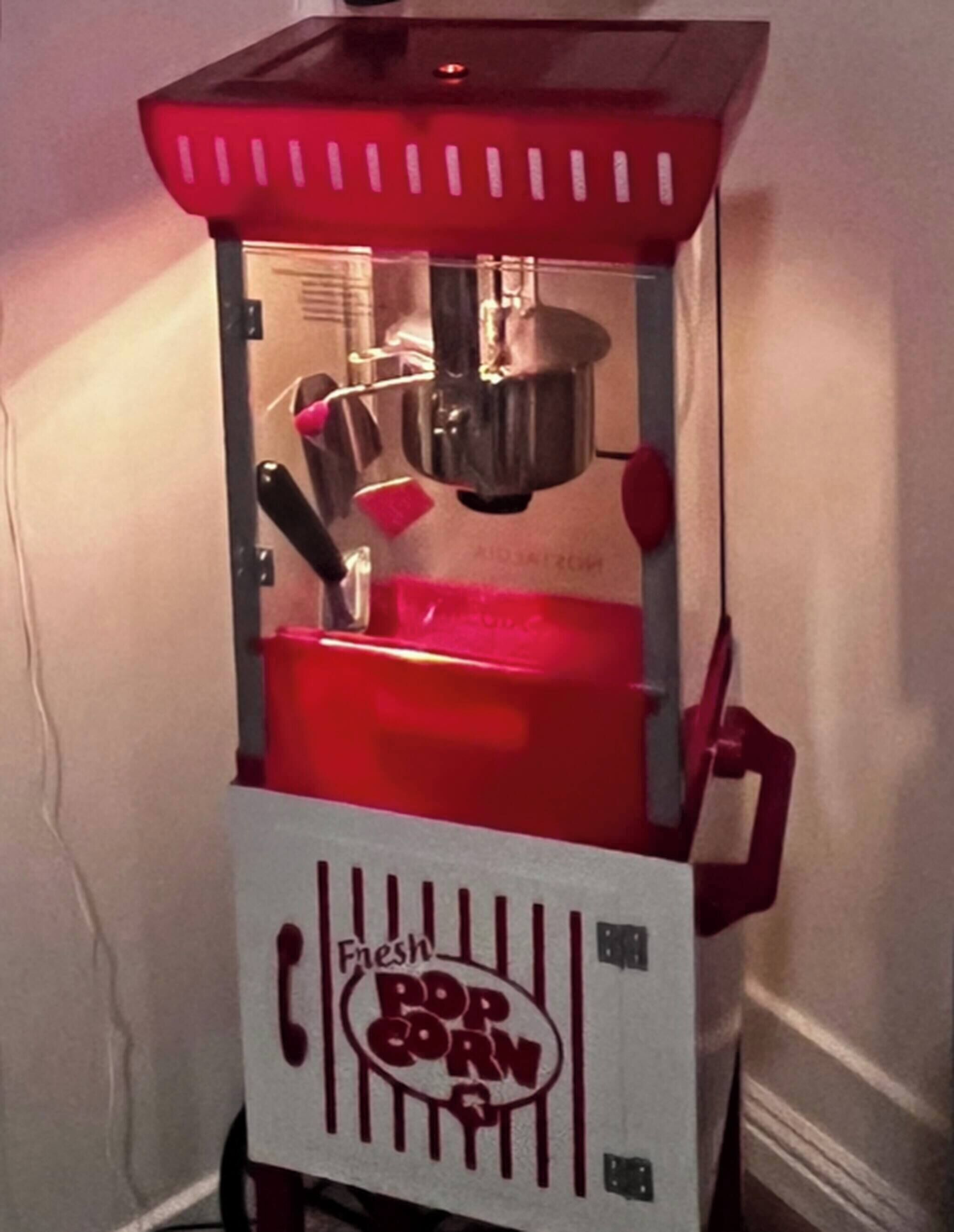 Eine alte Popcorn-Maschine mit der Aufschrift "Fresh Popcorn“, mit roter Oberseite und weißem Sockel.