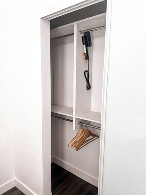 A closet with shelves, a hanging rod, and a power strip. - Luxury Downtown Long Beach Hub. Centrally located for every need. (Long Beach)