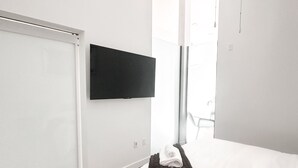 Ein modernes Hotelzimmer mit Bett, Flachbildfernseher an der Wand, einem gemusterten Teppich und einem Fenster mit Blick.