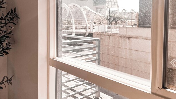 Ein Fenster mit Blick auf eine Außenanlage, die eine Brücke und Gebäude zeigt.