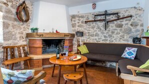 Un salon chaleureux avec un mur en pierre, une cheminée, un canapé et une table en bois sur laquelle se trouvent une bouteille et des verres.
