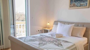 A bedroom with a bed, a nightstand, a lamp, and a painting on the wall.