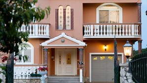 A two-story house with a balcony, a garage, and a front door.
