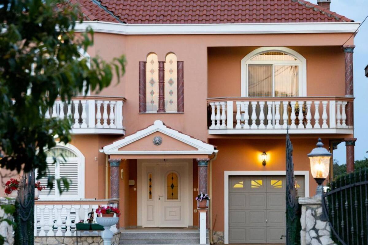 A two-story house with a balcony, a garage, and a front door.