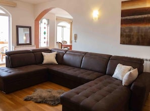 A modern living room with a large L-shaped sectional sofa, a fur rug, and a painting on the wall.