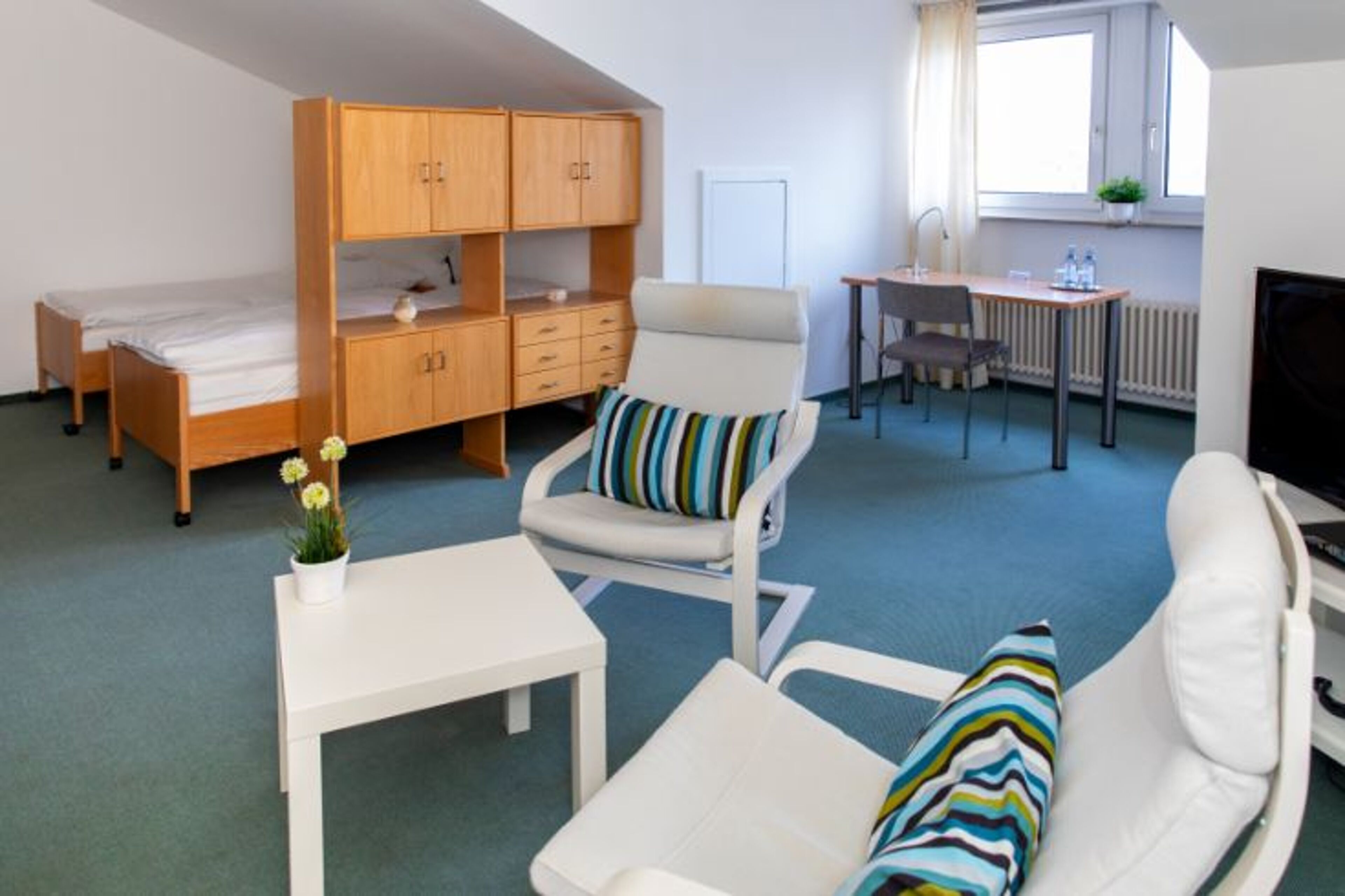A compact room with a bunk bed, a desk, a chair, and a small table.
